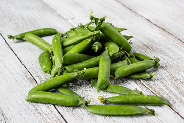 green peas pods on a white wooden table