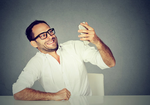 young funny looking man taking pictures of him self with smart phone