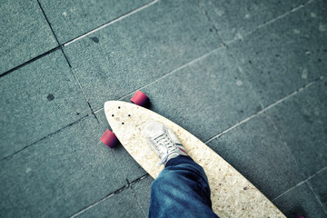 Point of view of a person leg on longboard on blurred city street. Personal perspective and tilt...