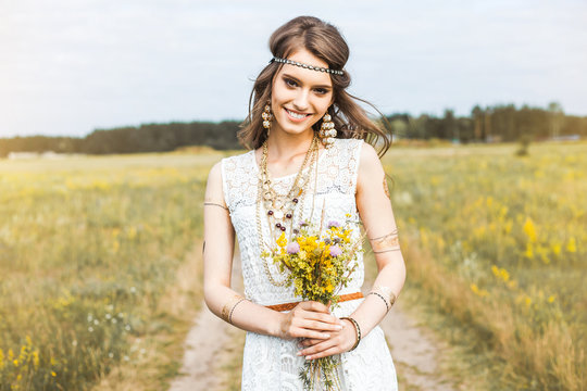 Close-up portrait of a beautiful young sweet gentle hippie girl in a white dress, holding a bouquet of wildflowers, walking outdoors, flash tattoo, indie, Bohemia, boho style, fashion accessories