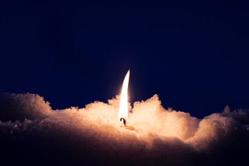 Fototapeta premium Candle burning in pile of melting snow