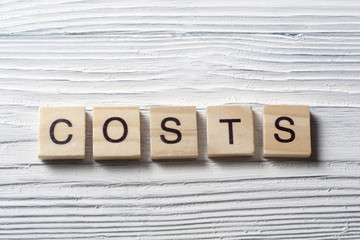 COSTS word concept on wood cubes. Wooden ABC