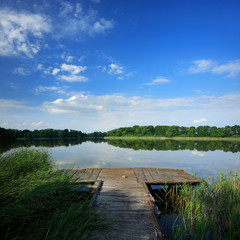 Fototapeta premium Old Wooden Pier on Lake under Blue Sky in Summer Landscape