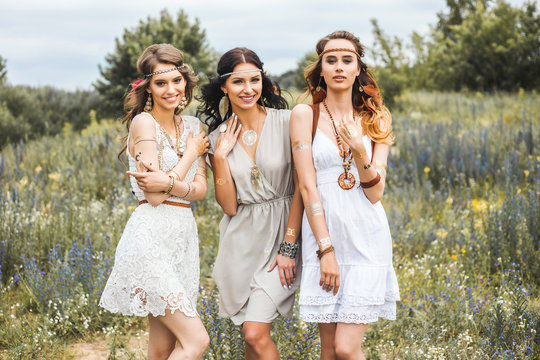 Summer holidays, travel and people concept -Three beautiful cheerful hippie girls, best friends, trendy hairstyles, feathers in her hair, white dress, tattoo flash, accessories, Bohemian, Boho Style