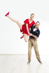 Rock'n'roll dance boogie woogie. Boogie acrobatic stunt in a studio on the white background. Dance for rock-n-roll music.