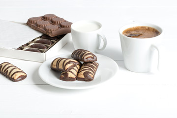 Cup of coffee and milk with cookies on a white wooden table