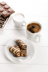 Cup of coffee and milk with cookies on a white wooden table