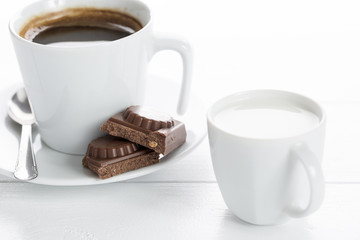 Coffee and chocolate on a white wooden table.