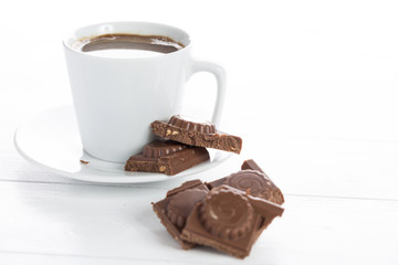 Coffee and chocolate on a white wooden table.