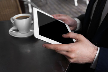 Businessman with coffee and tablet in cafe