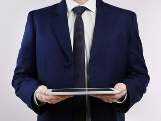Businessman with tablet on light background
