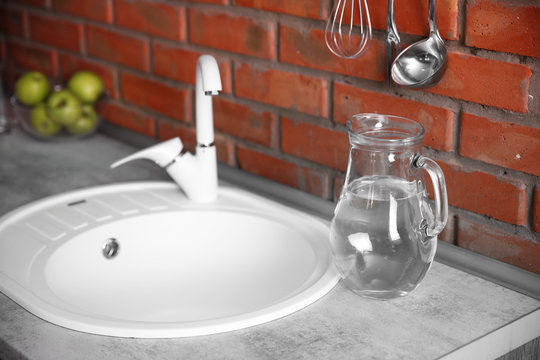 Glass jug of water and white sink at kitchen