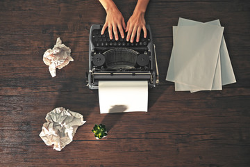 Woman hands working with retro typewriter and sheet of paper on wooden background