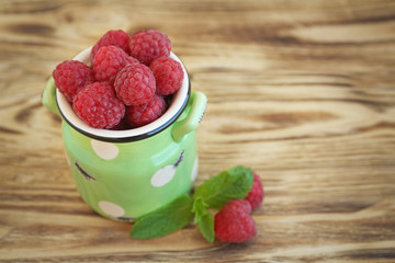 Fresh raspberry in watering can on wooden table