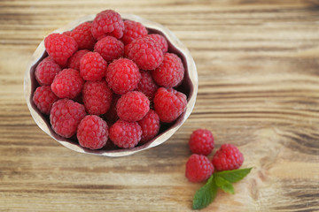 Fresh raspberry in bowl on wooden table