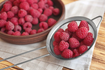Fresh raspberry in sieve and plate, closeup
