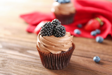 Tasty chocolate cupcakes with berries on wooden background
