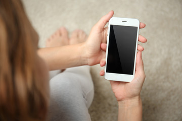 Woman holding smartphone on blurred carpet background