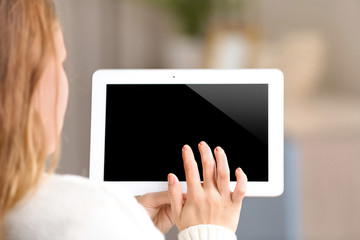Woman holding tablet on blurred room background