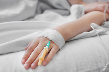 Obraz na płótnie Canvas Girl hand with drip infusion on bed