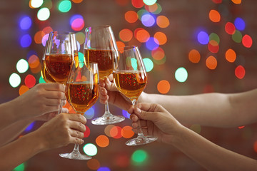 Female hands clinking glases with white wine on bokeh background