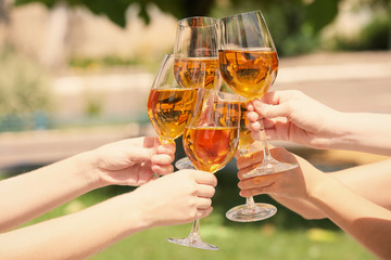Female hands clinking glasses with white wine outdoors
