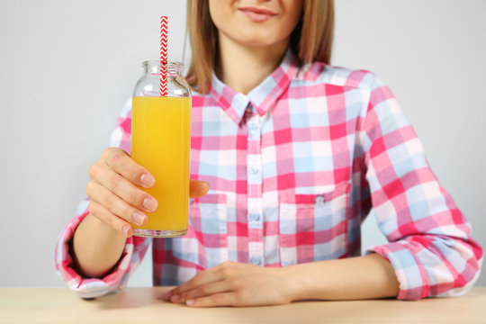 Young woman with glass of fresh juice sitting at the table