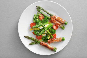 Grilled asparagus with bacon and vegetables on plate