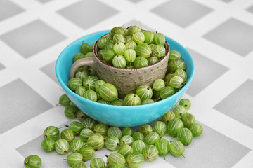 Gooseberries with cup and bowl on table