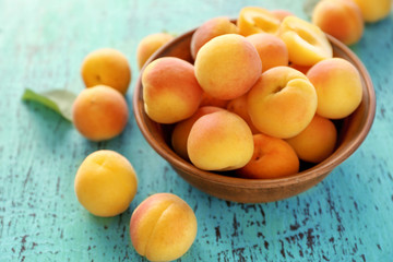 Fototapeta na wymiar Fresh juicy apricots in bowl on wooden table