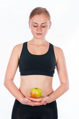 Beautiful young blonde woman with an apple in his hand. A young athletic woman holding a big green apple in her hand