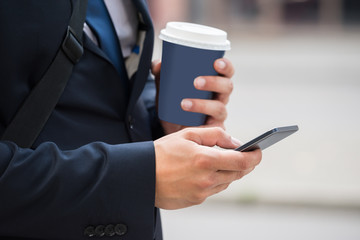 Businessperson Hand With Mobile Phone And Coffee Cup