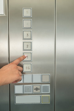 Female's Hand Pressing First Floor Button In Elevator
