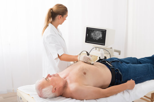 Doctor Using Ultrasound Scan On Abdomen Of Male Patient