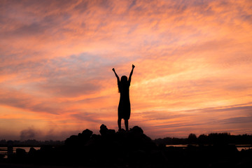 silhouette woman Happy celebrating winning success at sunset