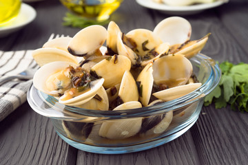 bowl full of clams with sauce glass on wood