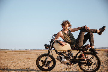 Obraz premium Young brutal man laying on his motorcycle and posing