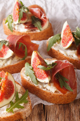 Healthy sandwiches with figs, prosciutto, arugula and cheese close-up. Vertical
