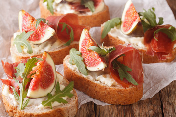 Healthy sandwiches with figs, prosciutto, arugula and cheese close-up. Horizontal
