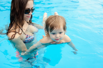 Fototapeta na wymiar Young mother with her little daughter in the pool