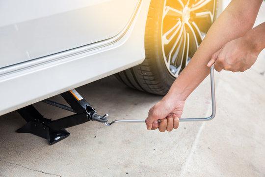 Hand lifting a car with spanner jack-screw