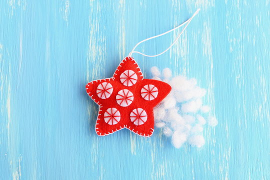 Stuff the felt Christmas star with hollowfiber. Christmas sewing craft. Red hanging star ornament decorated with white balls on a blue background. How to teach a child to sew. Tutorial. Step. Top view