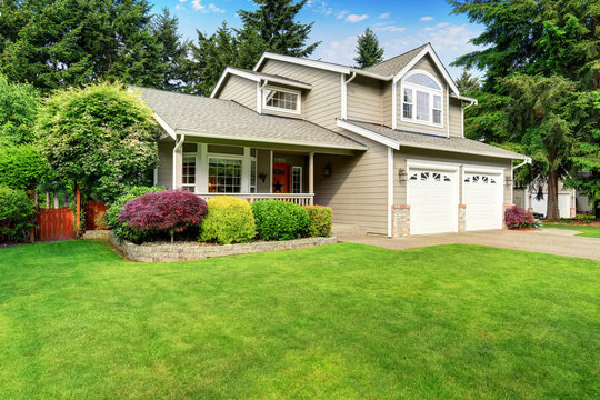 American House Exterior With Double Garage And Well Kept Lawn.