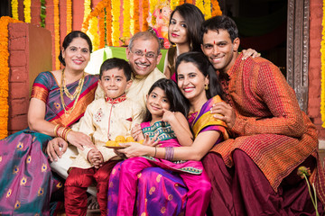 Indian family celebrating ganesh festival or diwali, eating sweets, taking selfie and other...