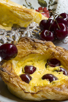 Plundergeb&auml;ck mit Vanillecreme und Kirschen mit frsichen Kirschen im Hintergrund