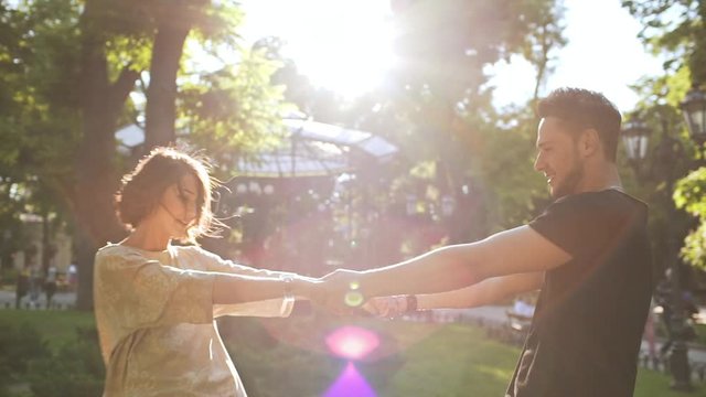 Young beautiful couple rejoicing, smiling, walking in park. Slow motion.
