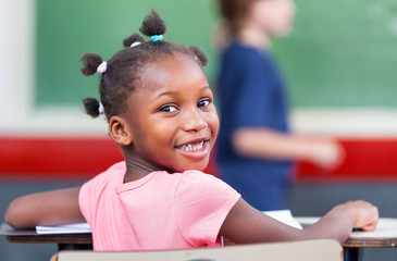 Cheerful african girl smiling in primary classroom