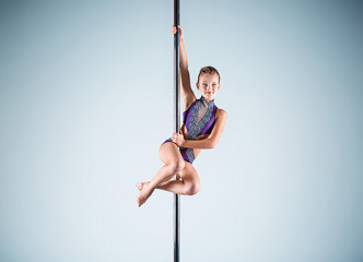 The strong and graceful young girl performing acrobatic exercises on pylon