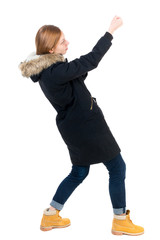 Side view. girl in winter jacket pulls his hands on top of the rope   Standing young girl in parka. Rear view people collection.  backside view of person.  Isolated over white background. The girl in