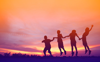 Fototapeta premium shutter stock : Happy kids silhouettes having fun on meadow at